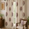 Off-white floral tree print curtain with pink flowers and grey leaves on a living room window, paired with a matching printed cushion on a wooden chair in an elegant Indian home.