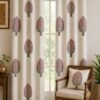 Off-white floral tree print curtain with pink flowers and grey leaves on a living room window, paired with a matching printed cushion on a wooden chair in an elegant Indian home.