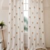 Elegant white sheer curtain with small orange floral prints, displayed on a large arched window in a warm minimalist room.