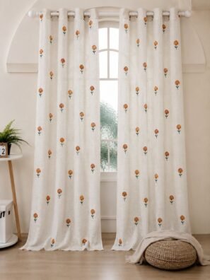 Elegant white sheer curtain with small orange floral prints, displayed on a large arched window in a warm minimalist room.