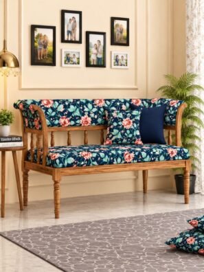 Wooden sofa upholstered in navy blue floral fabric featuring coral pink flowers, mint green leaves, and tiny multicolored floral accents.