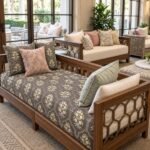 Wooden daybed upholstered in dark grey fabric with small yellow floral motifs, pale blue-grey leaves, and delicate white arch patterns.